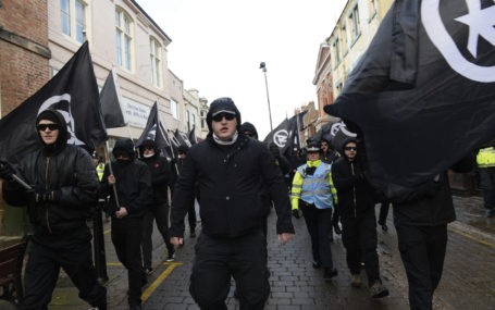 Members of National Action protesting, wearing all black and covering their faces